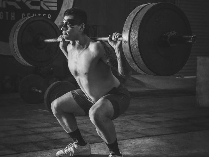 Athletic male hands holding a heavy metal barbell.