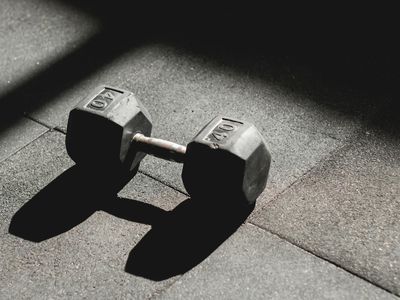 Black dumbbells lying on a professional gym floor.