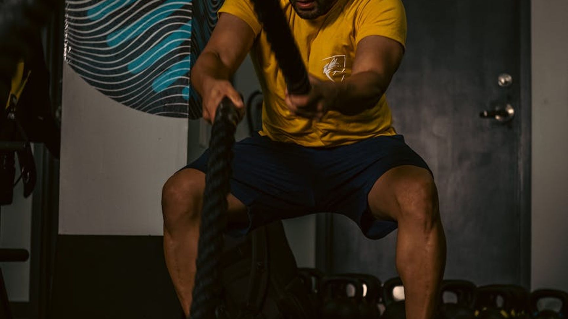 Man performing strength exercise in a dark gym setting.